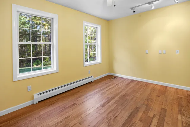 an empty room with wooden floor and windows