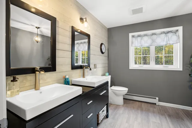 a bathroom with a double vanity sink toilet and mirror