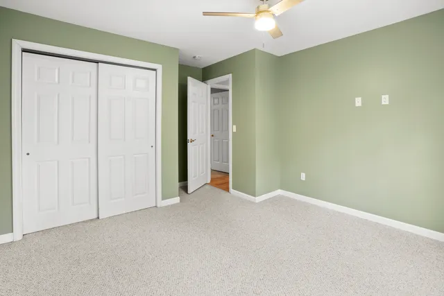 an empty room with a chandelier fan and closet area