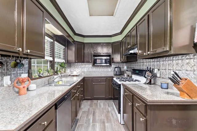 a kitchen with stainless steel appliances granite countertop sink stove top oven and cabinets