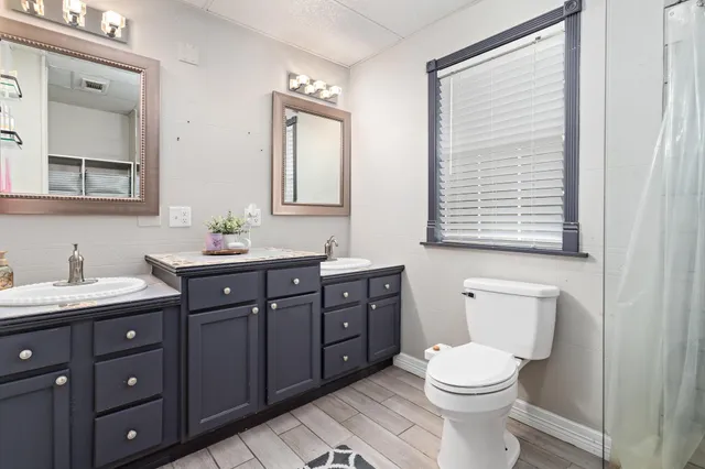 a bathroom with a toilet a sink a vanity a mirror and a window