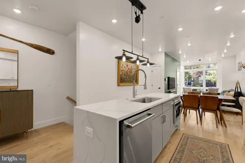 a kitchen with a sink appliances and wooden floor
