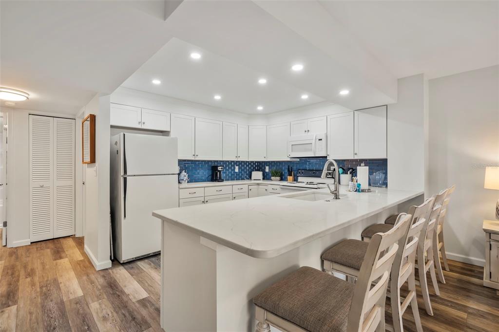 2810 North Beach Road, Unit 106 Englewood, FL 34223 - Photo 7 of 28 a large kitchen with kitchen island a stove a table and a refrigerator