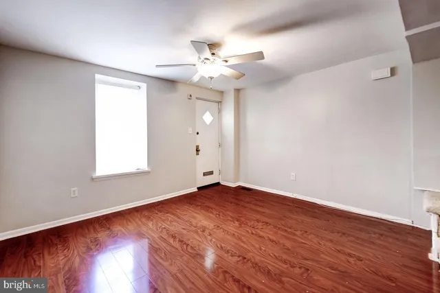 an empty room with wooden floor fan and windows