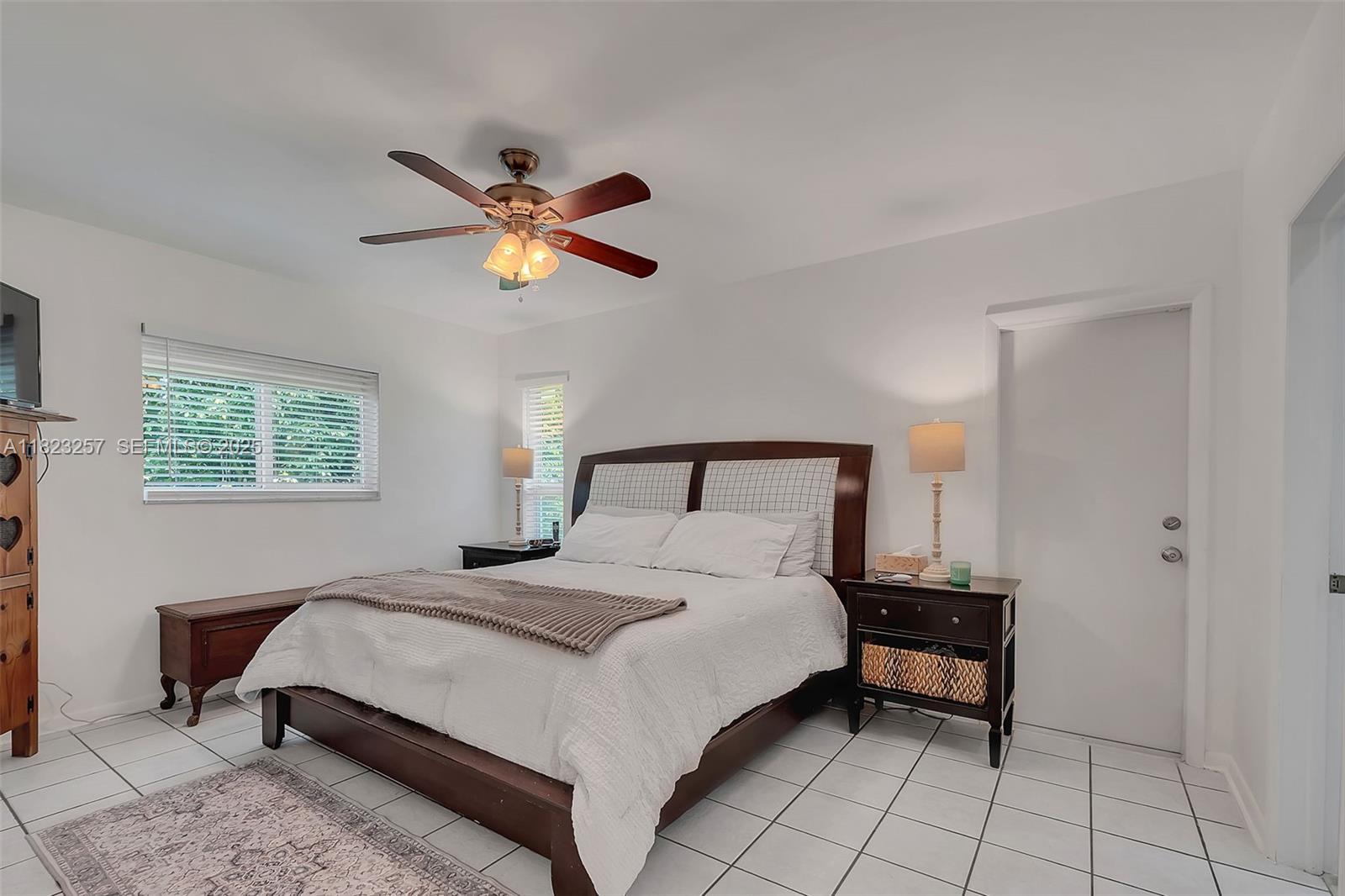 7340 Southwest 123rd Terrace Pinecrest, FL 33156 - Photo 14 of 30 a bedroom with a bed and a chandelier
