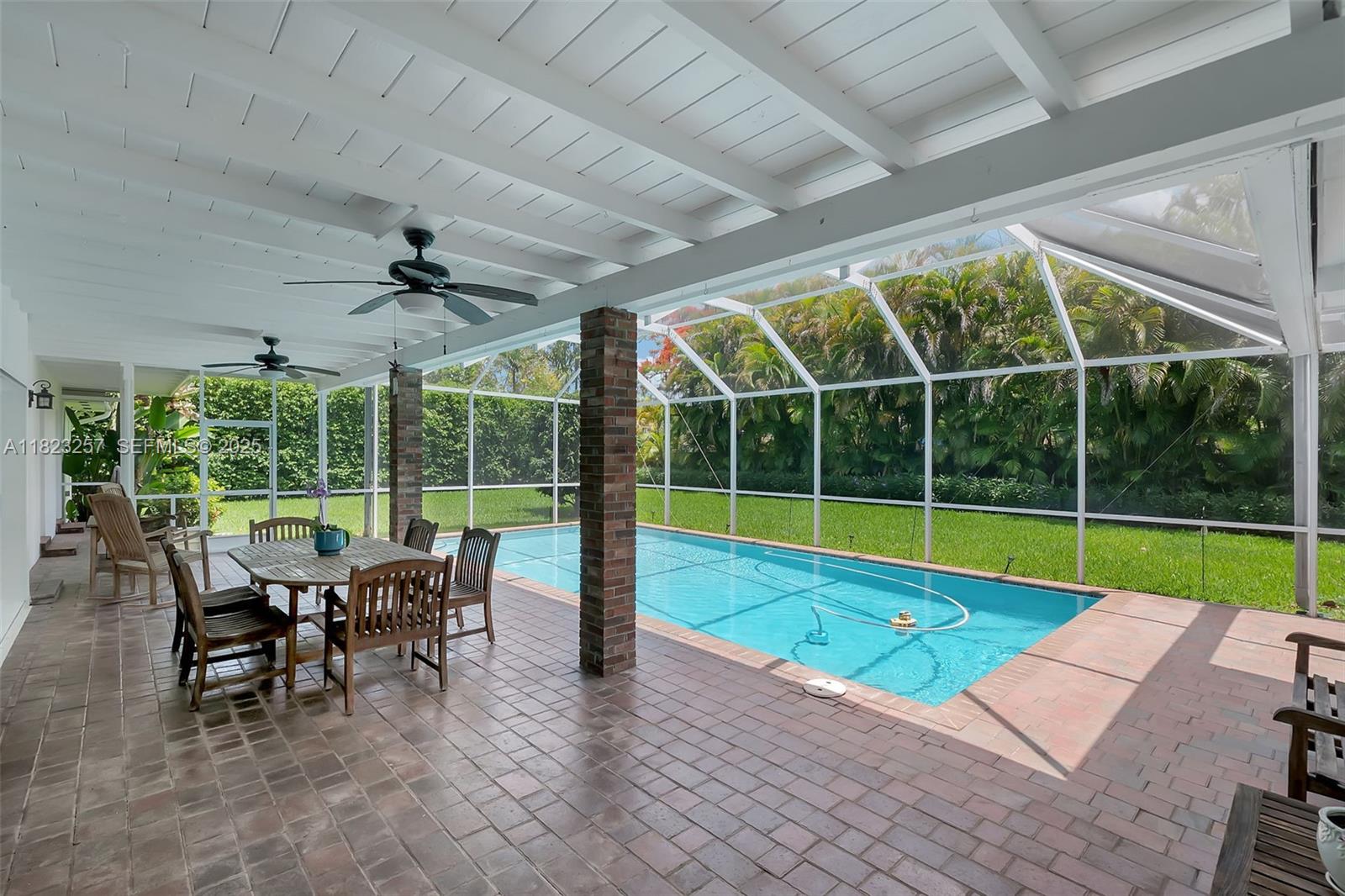 7340 Southwest 123rd Terrace Pinecrest, FL 33156 - Photo 22 of 30 a view of a swimming pool with a table and chairs in front of it