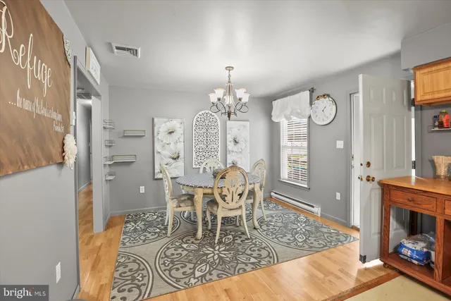 a dining room with wooden floor a chandelier a wooden table and chairs