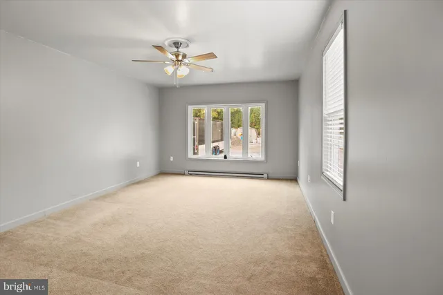 an empty room with windows and fan