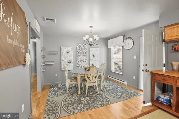 a dining room with wooden floor a chandelier a wooden table and chairs