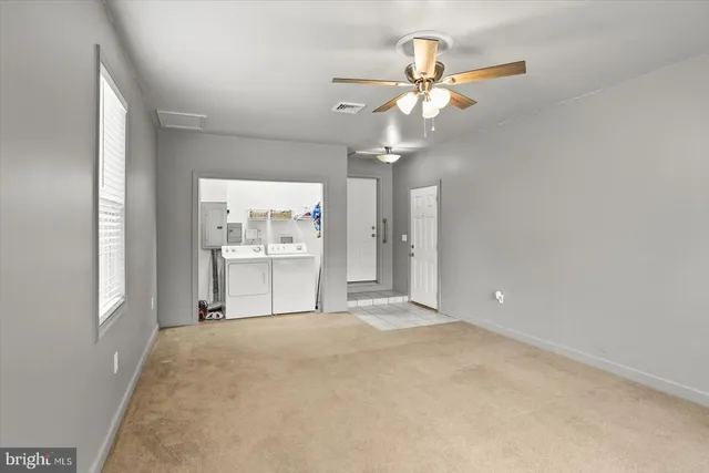 a view of a livingroom with a chandelier fan and windows