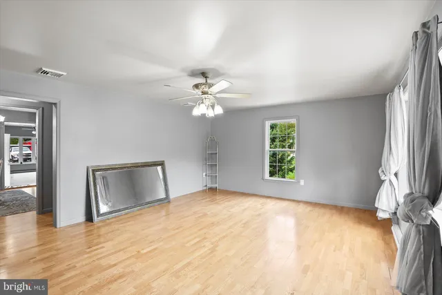 a view of an empty room with window and wooden floor