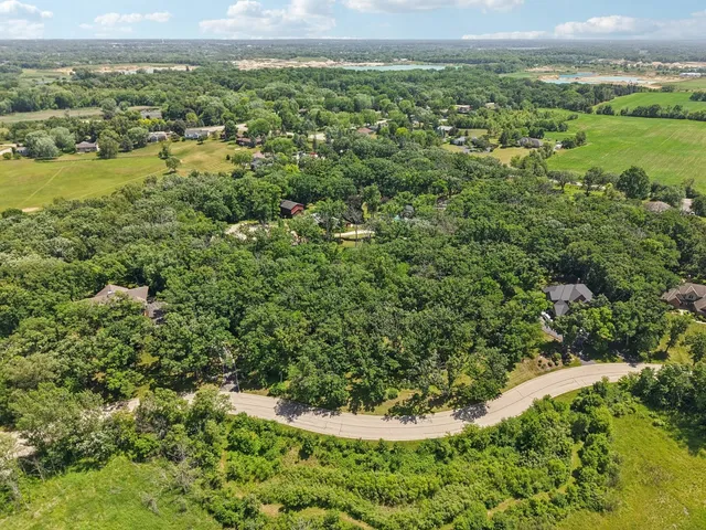 an aerial view of residential house with outdoor space and trees all around
