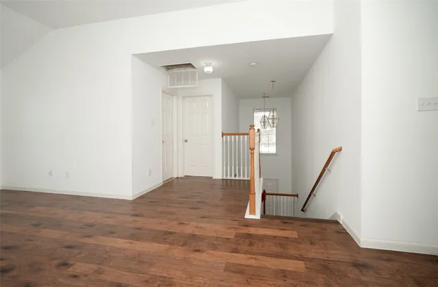 an empty room with wooden floor ceiling fan and windows