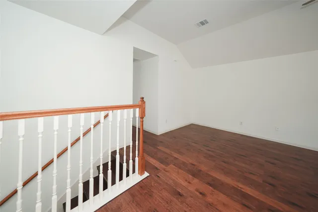an empty room with wooden floor ceiling fan and windows