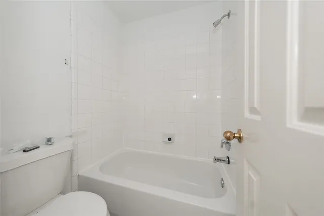 a white bath tub sitting next to a white toilet and vanity