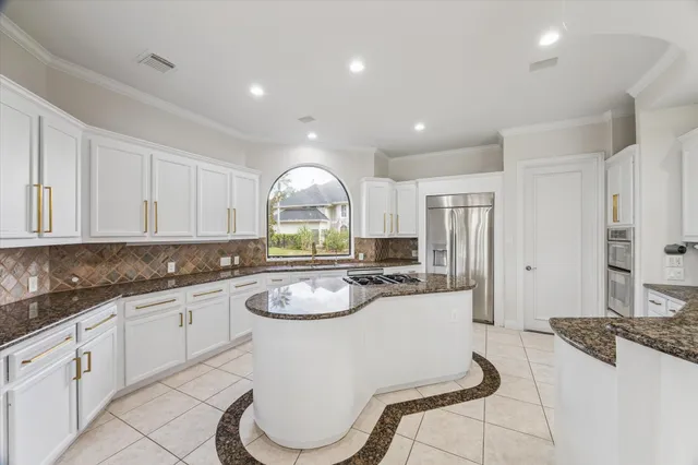 a large white kitchen with stainless steel appliances kitchen island granite countertop a stove a sink a dining table and chair