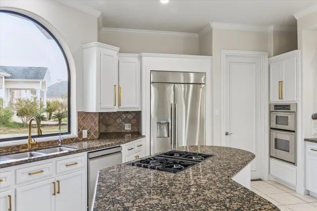 a large white kitchen with a large window a sink and cabinets