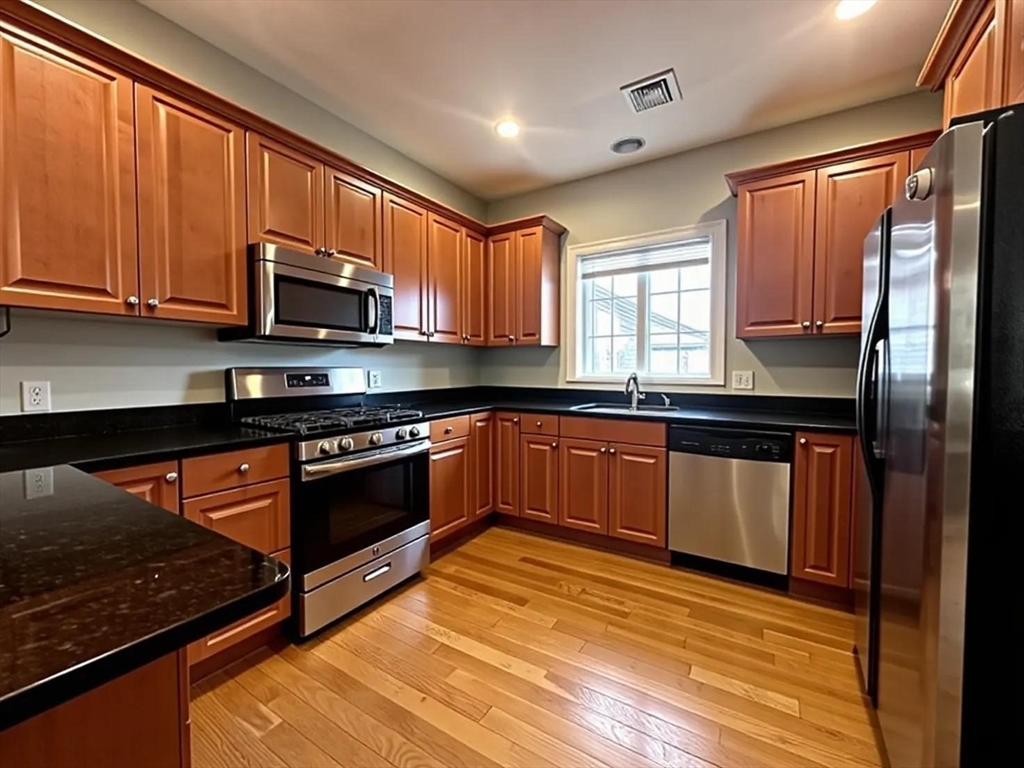 6 Wyman Street, Unit 3 Boston, MA 02130 - Photo 3 of 9 a kitchen with stainless steel appliances granite countertop wooden cabinets a stove top oven a sink and dishwasher