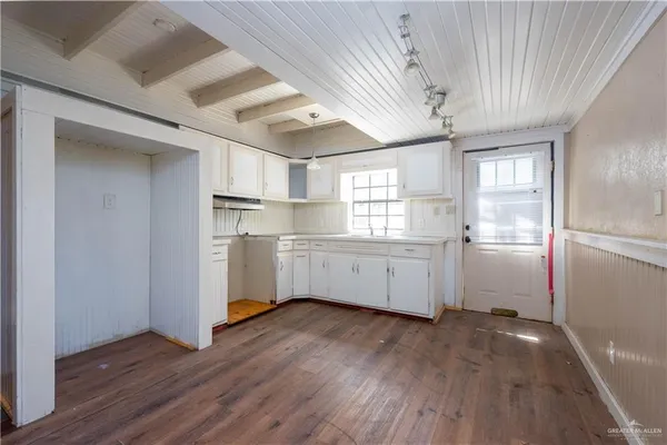 a kitchen with a refrigerator a sink dishwasher a stove and white cabinets with wooden floor