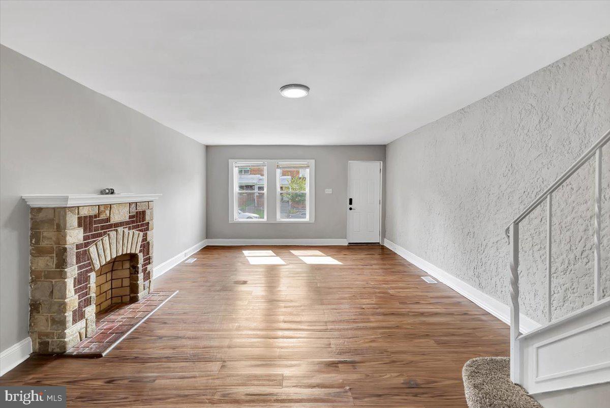 74 South Kossuth Street Baltimore, MD 21229 - Photo 11 of 18 a view of empty room with wooden floor and fireplace