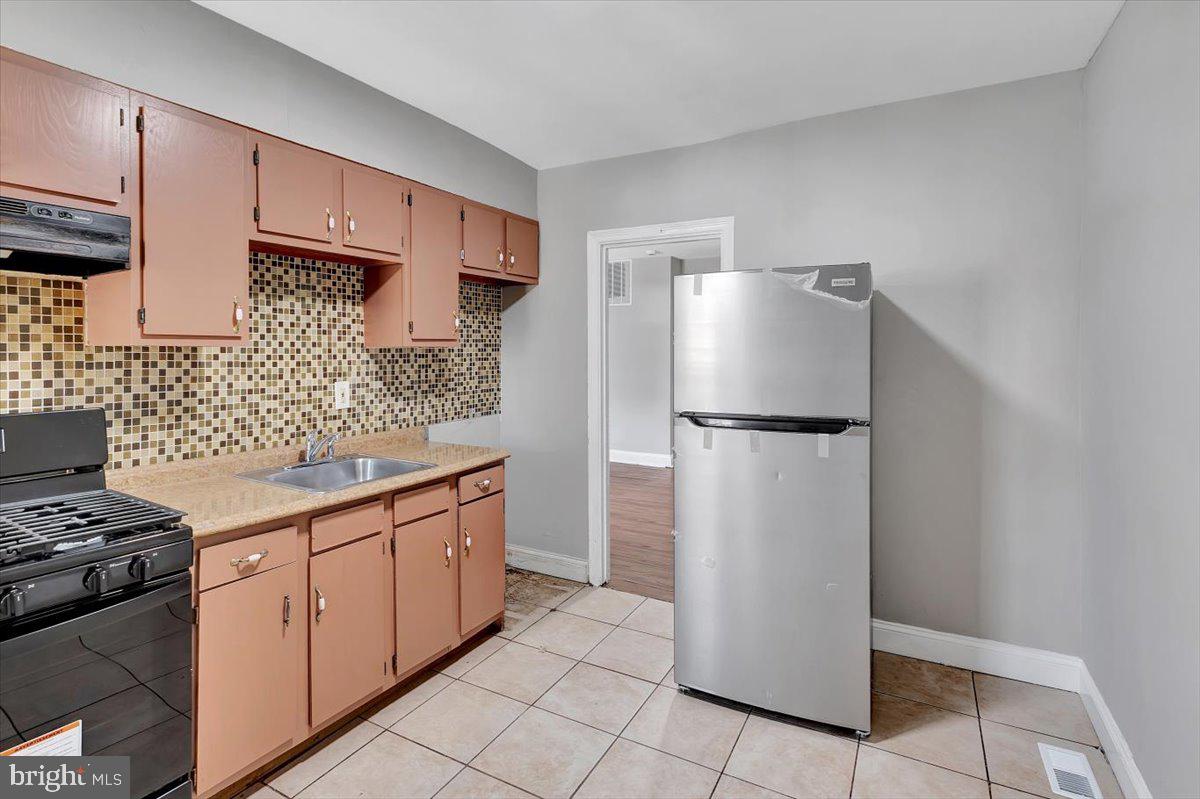74 South Kossuth Street Baltimore, MD 21229 - Photo 10 of 18 a kitchen with stainless steel appliances a refrigerator sink and stove