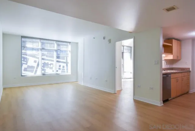 an empty room with wooden floor cabinet and windows