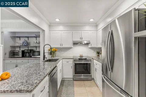 a kitchen with stainless steel appliances granite countertop a refrigerator and a stove top oven