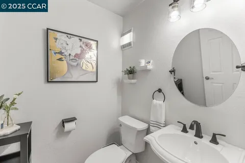 a bathroom with a granite countertop toilet a sink a mirror and a shower