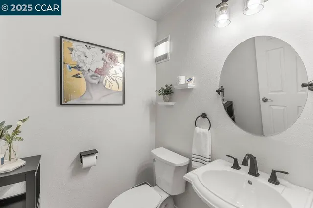 a bathroom with a granite countertop toilet a sink a mirror and a shower