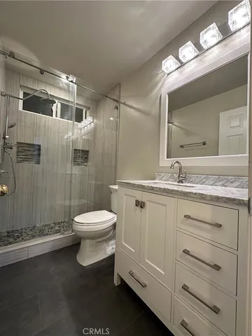 a bathroom with a granite countertop sink toilet a mirror a vanity and shower