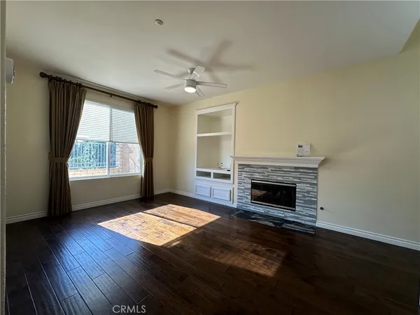 an empty room with windows fireplace and wooden floor