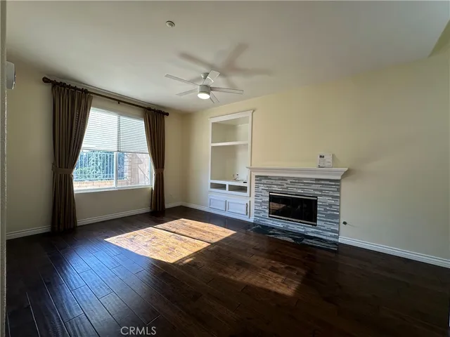 an empty room with windows fireplace and wooden floor