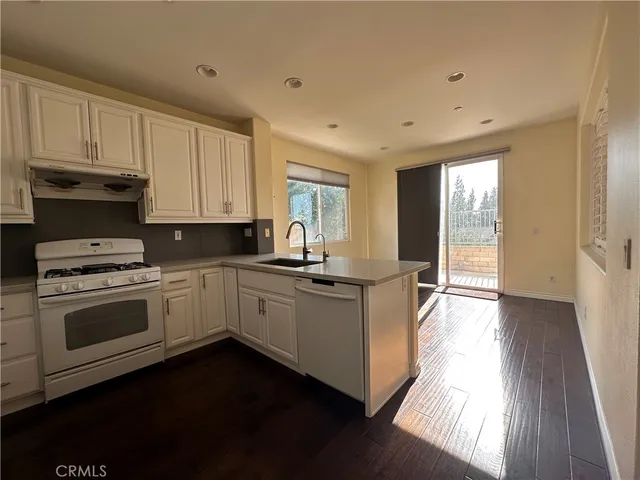a kitchen with granite countertop white cabinets and white appliances