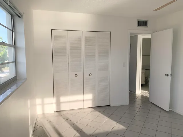 a view of a room with a large window and chandelier fan