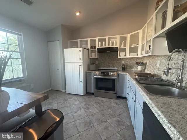 a kitchen with kitchen island granite countertop a sink cabinets and stainless steel appliances