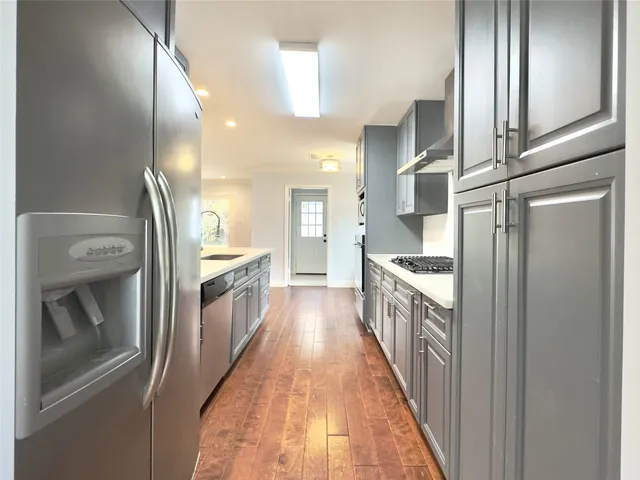 a view of kitchen with kitchen island wooden floor center island and stainless steel appliances