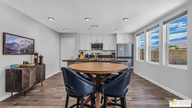 a dining hall with stainless steel appliances granite countertop a sink a stove a dining table and chairs with wooden floor