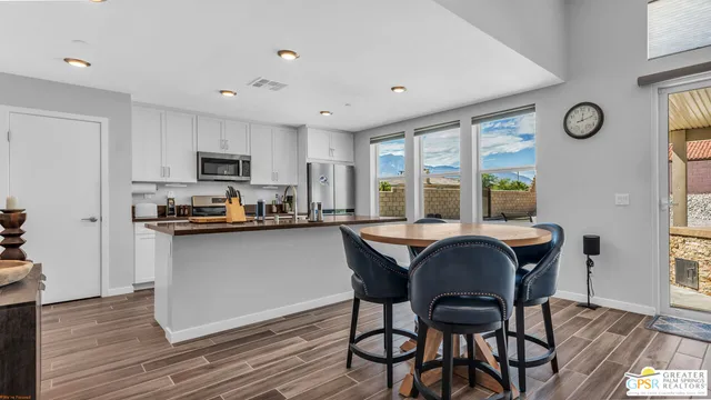 a kitchen with a table chairs a sink dishwasher refrigerator and cabinets