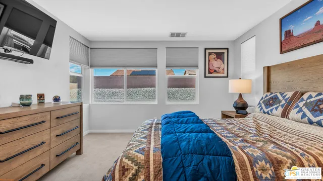 a bedroom with a bed a flat screen tv and windows