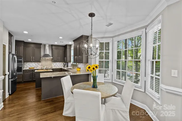 a kitchen with stainless steel appliances granite countertop a stove and a dining table with wooden floor