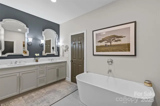 a spacious bathroom with a tub a double vanity sink and a mirror