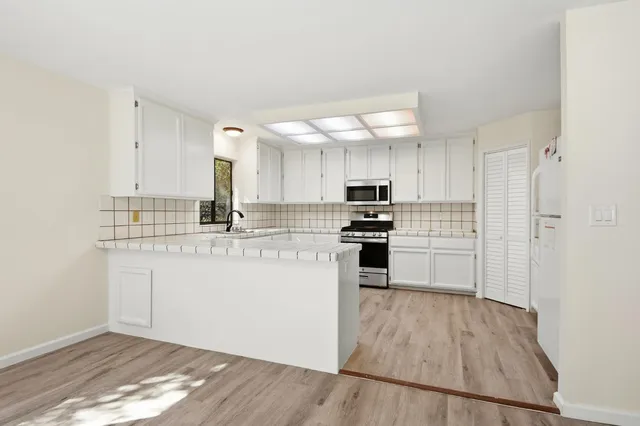 a kitchen with granite countertop a sink cabinets and wooden floor