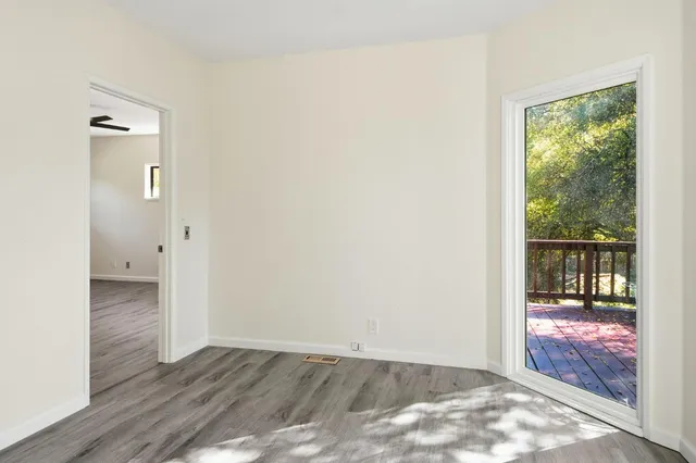 an empty room with wooden floor chandelier fan and windows