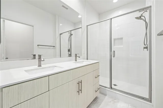 a bathroom with a double vanity sink mirror and shower