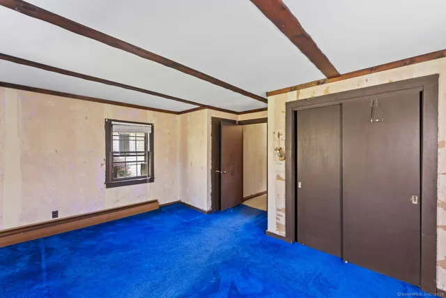 a view of an empty room with wooden floor and closet