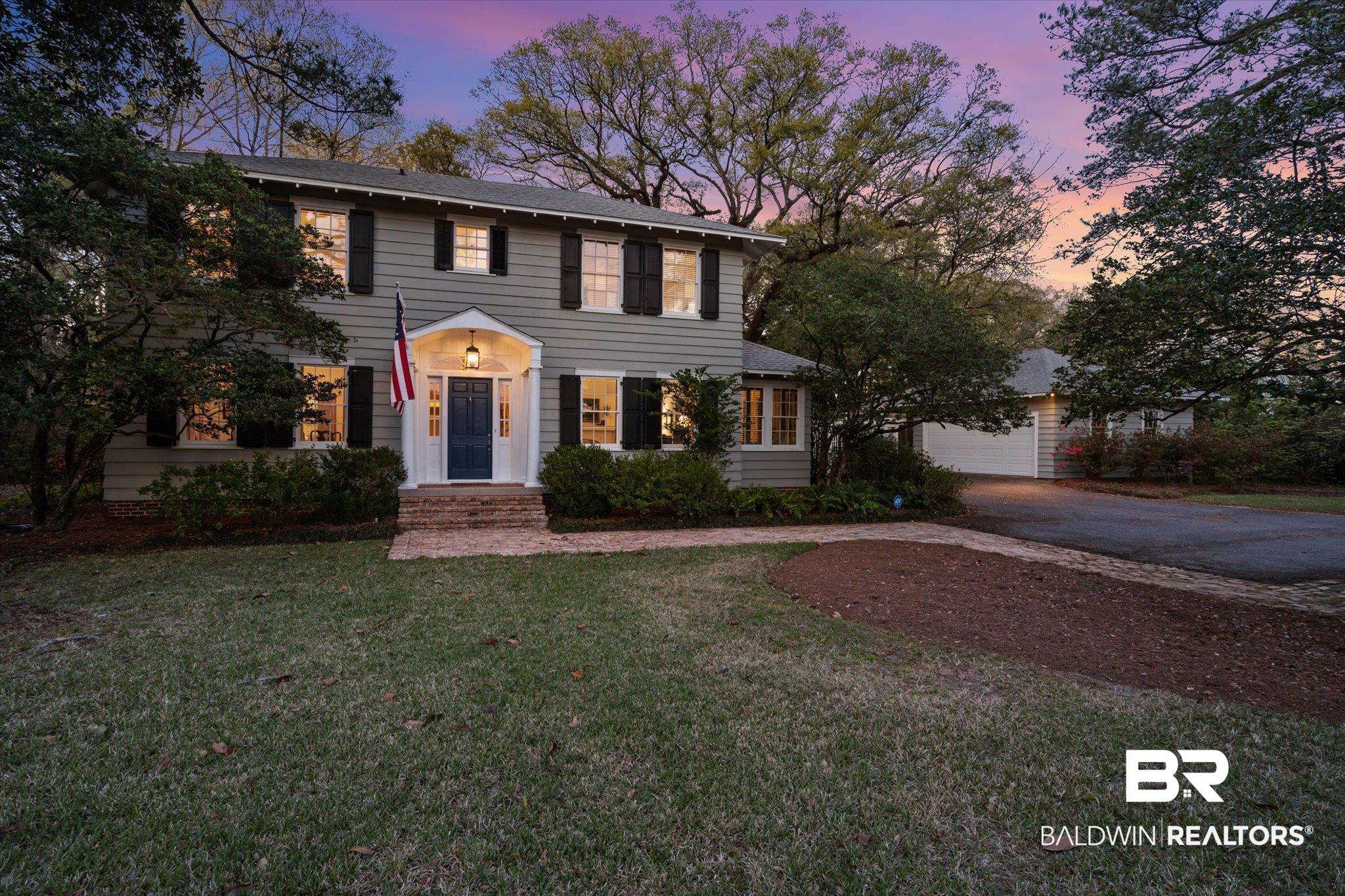 Colonial-style house featuring a front lawn, driveway, a garage, and an outbuilding