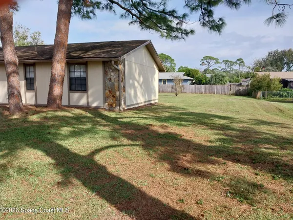 a view of a house with a backyard and a tree