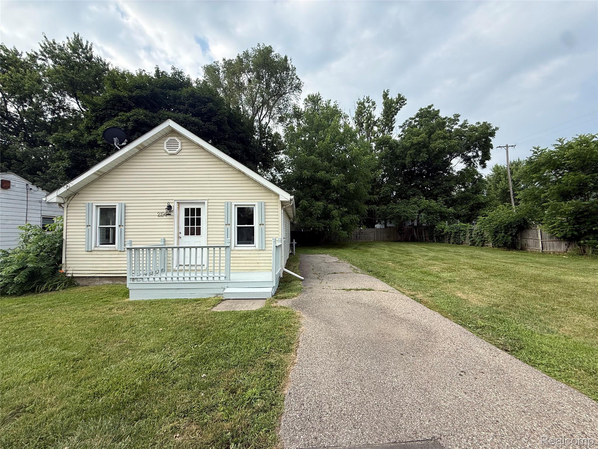 2194 East Bristol Road Burton, MI 48529 - Photo 2 of 13 Cream-colored siding exterior featuring a front porch with light blue railings, an arched gable vent, and light blue window shutters