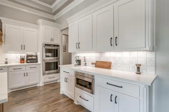 a kitchen with granite countertop white cabinets and stainless steel appliances