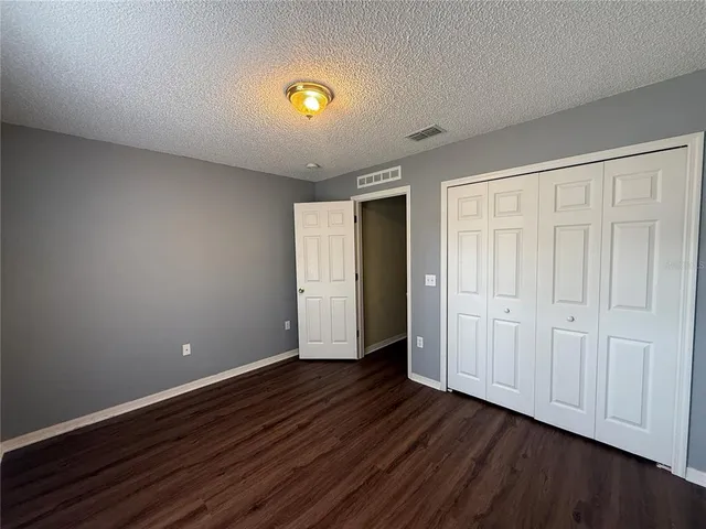 a view of an empty room with wooden floor and closet